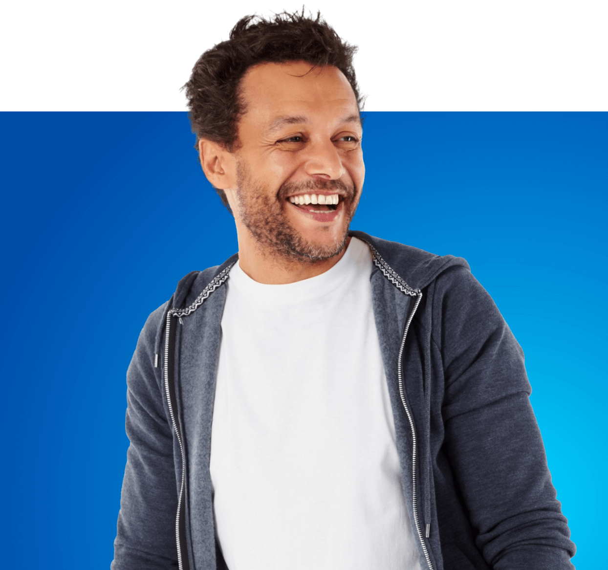 Man looking wearing a white shirt and grey jacket looking away and to the right while smiling.